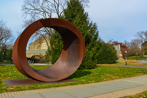Princeton, NJ, USA - November  12, 2019: art object, a cut circle of metal near the educational building of Princeton University. New Jersey USA