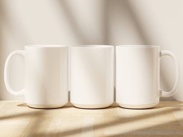 istock Three 15 oz Ceramic Mugs with Shadows from Windowpane on a Wooden Floor 1978413712