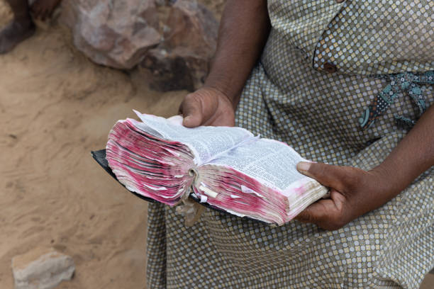 close up book, hands of old african woman reading the bible in the yard, village in Botswana