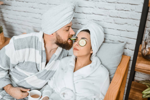 istock Male Eating Cucumber Slices From Girlfriend's Eyes While She Naps After Bath 1978421668