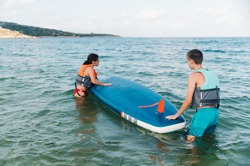 Teenagers enjoying summer days on a vacation. Having fun enjoying SUP paddle boarding on the sea