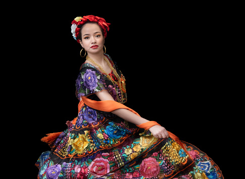 Whirlwind of tradition and color: Mexican dancer showcases Chiapas attire with flower embroidery, bow braid, and a lively, multicolored shawl.