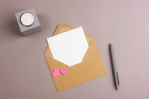 Envelope with blank card, hearts and candle on gray background. Valentines day concept, top view, flat lay, mockup.