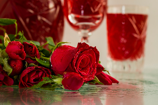 Traditional Turkish Red Rose Sherbet in crystal glasses on white surface with fresh red roses.Ottoman Cuisine stylized