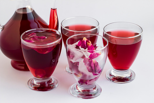 Fragrant red rose sherbet served in glass pitcher and glasses with rose petals and ice.An old Ramadan Drink from Ottoman Cuisine