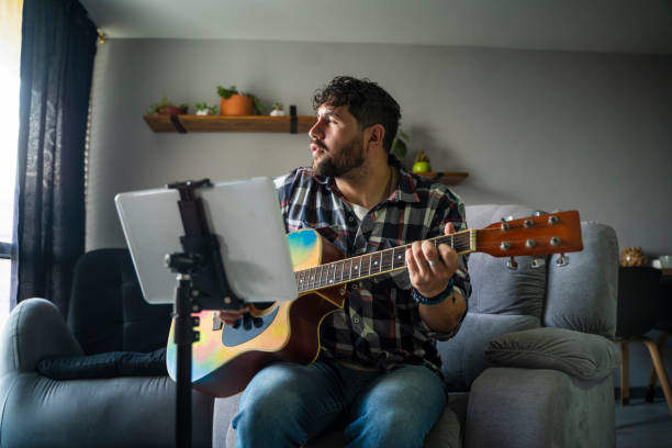 istock young man playing guitar in his living room 1978463063