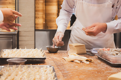 Close-up detail  of food prep at a Chinese restaurant kitchen as staff assemble dim sum dumplings in Taipei, Taiwan.