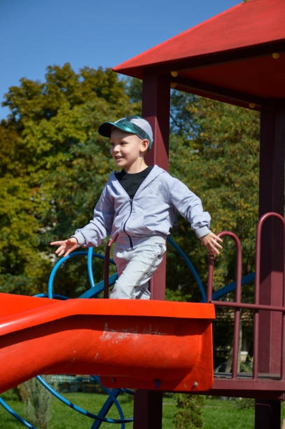 istock a cheerful boy with a charming smile rides on a slide. the child smiles 1978472434