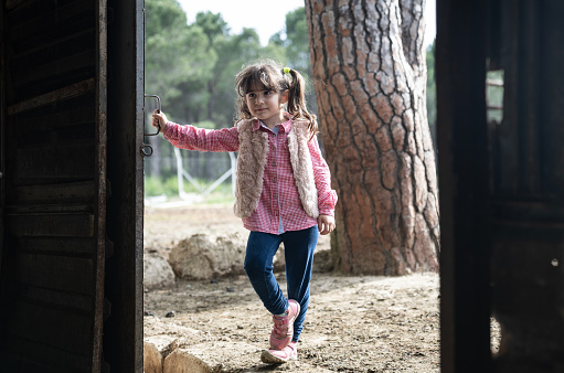 Photo of 5 years old girl wearing a plaid shirt and jeans in countryside. Shot under daylight with a full frame mirrorless camera.