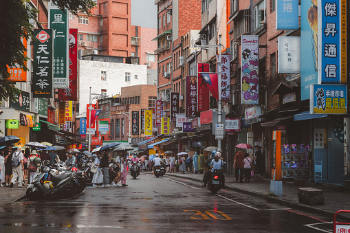 Taipei, Taiwan - October 1, 2023: Busy, colourful urban people and street scenes in the bustling Tamsui District, on a rainy day in Taipei, Taiwan.