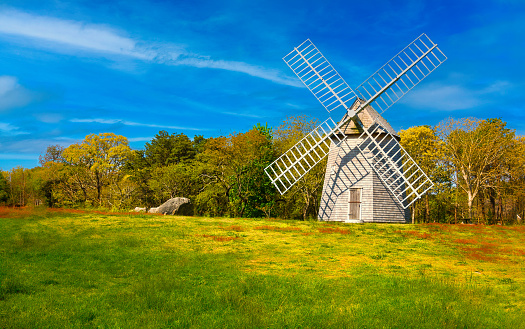 Springtime colors emerge from blooming trees behind the old Higgins Family Windmill in Brewster, Massachusetts on a bright May morning.