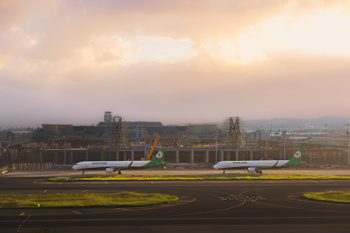 Taipei, Republic of China - October 2, 2023: A pair of Eva Air Airbus A321-211 aircraft parked by the runway at Taiwan Taoyuan International Airport during sunset or sunrise.