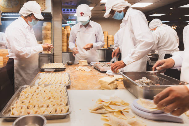 Din Tai Fung, Taiwan Taipei, Taiwan - October 1, 2023: Food prep at a restaurant kitchen as staff assemble dim sum dumplings at Din Tai Fung at Taipei 101 in the downtown city Da'an District. chefs whites stock pictures, royalty-free photos & images