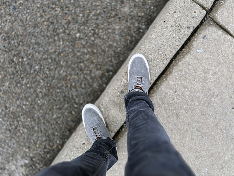 View of feet standing on a city curb.