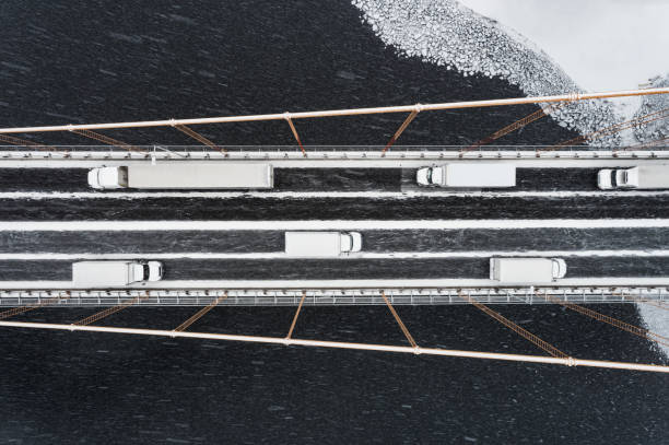 Aerial view of trucks crossing a suspension bridge during a blizzard. (Composite)