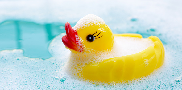 A tiny baby childrens bathtub with a towel and rubber ducks.
