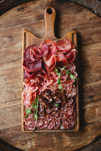 Food photography, cold cuts, sausages, jamon, dried meat on a wooden board.