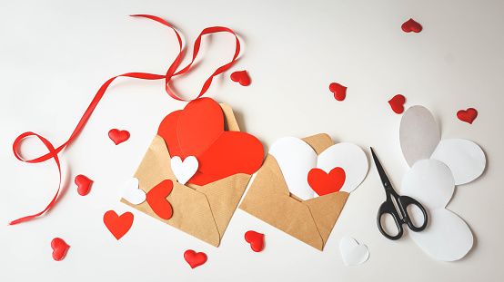 Children's creativity top view, cut out cardboard hearts and envelopes, handmade gift.