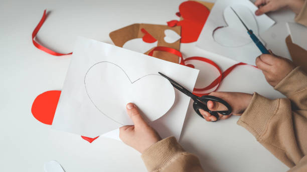 istock Child cuts out a postcard from paper, creativity for mom 1978613465