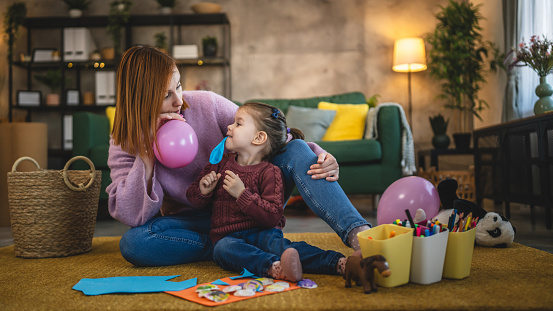mother and daughter toddler girl play with balloons at hoe family bonding concept