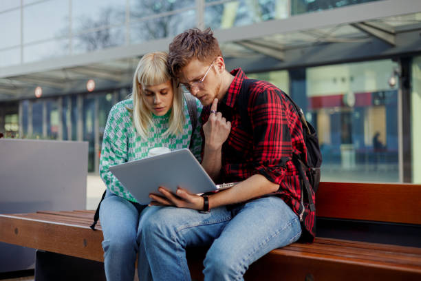 istock Students sitting on a bench and looking at the laptop. 1978647692