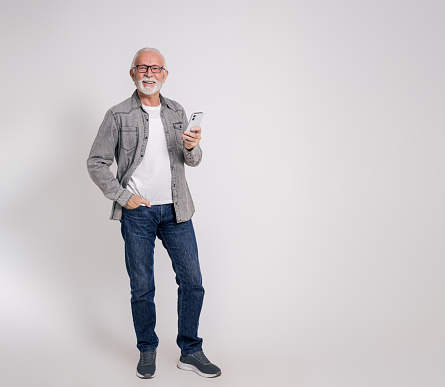 Portrait of confident old male professional with smart phone smiling at camera on white background