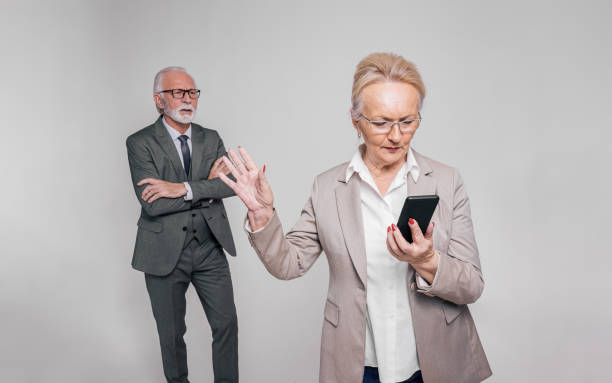 istock Senior female executive using smartphone and showing stop gesture to businessman on white background 1978680650