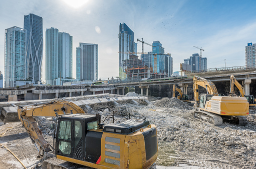 Yellow excavator loader at construction site with raised bucket over blue sky.