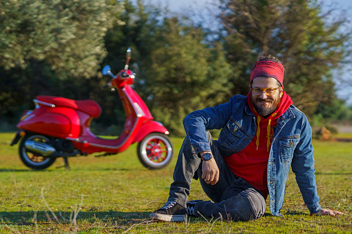Casual mid adult man posing with his scooter on grass
