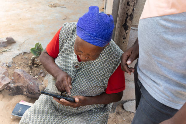 village african old woman learning to use a mobile phone with the help of a volunteer