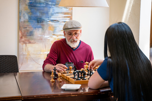 Nurse is playing chess with an elderly man in the retirement home