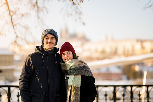 Happy young couple enjoying a winter day in the city and looking at camera.