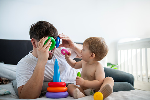 Cute little boy and his dad playing together with toys.