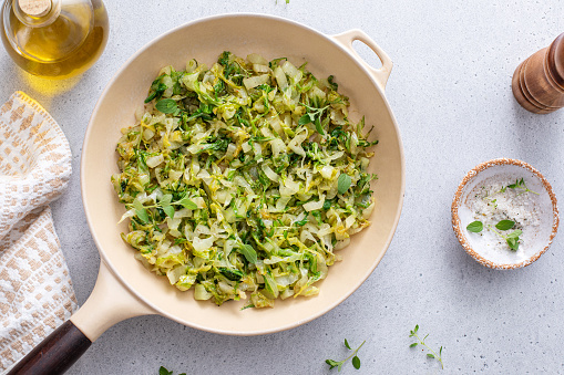 Sauteed cabbage with herbs in a cast iron pan, healthy vegetable side dish idea