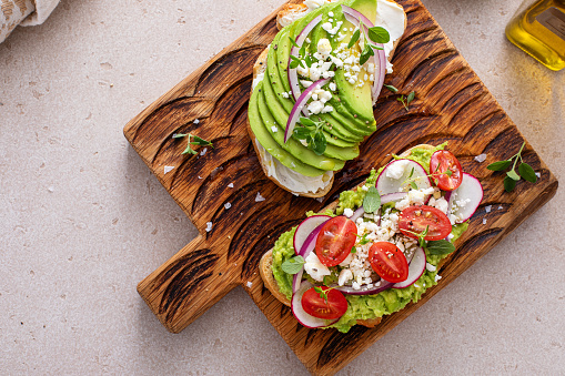 Avocado toasts with radishes, tomatoes and feta topped with olive oil, healthy breakfast idea