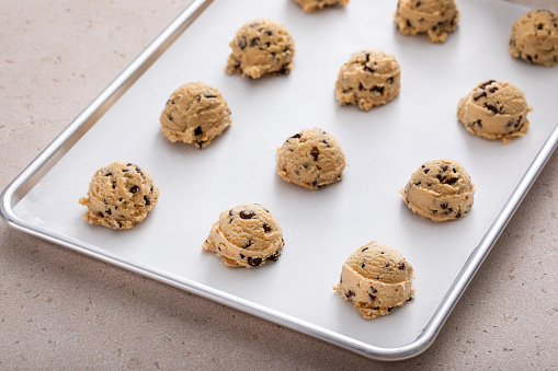 Chocolate chip cookie dough scooped on a cookie sheet ready to be baked