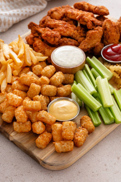 istock Fried chicken strips and french fries board with sauces and celery 1978755636