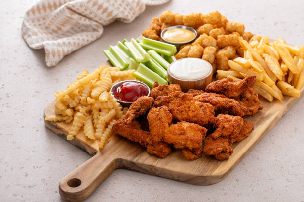 istock Fried chicken strips and french fries board with sauces and celery 1978755638