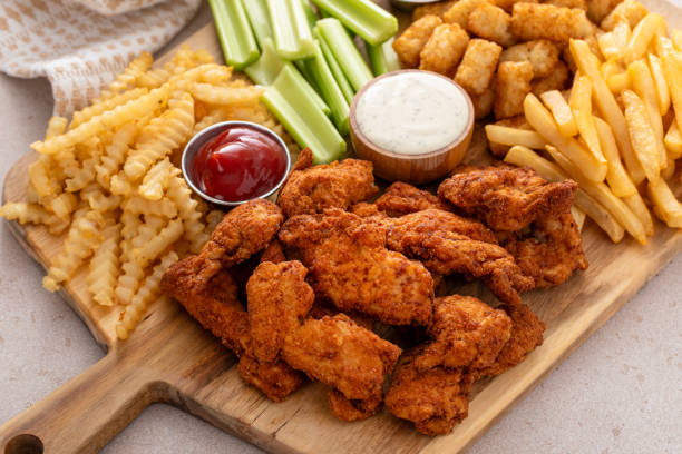 istock Fried chicken strips and french fries board with sauces and celery 1978755643