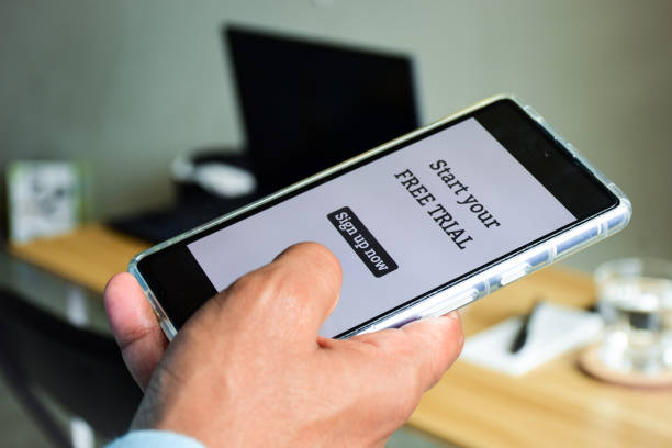istock Person using mobile phone displaying message start your free trial sign up now. Selective focus. 1978756727