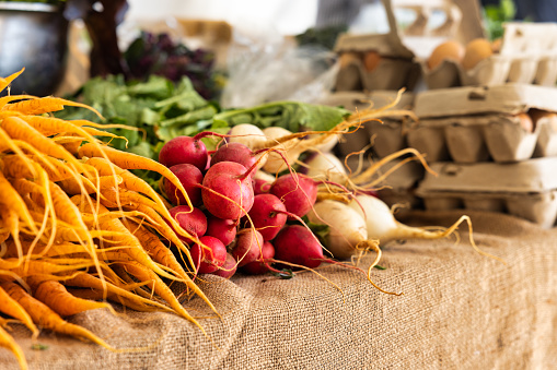farmers market stall with various fresh vegetables, carrot ,radish, leak and eggs