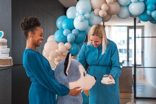 A glowing mom-to-be and her female friends enjoying a night of fun and celebration at a baby shower. The expectant Caucasian mother is beaming with happiness as she receives gifts and well-wishes from her loved ones.