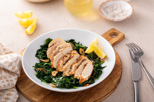 Grilled chicken served with sauteed spinach with garlic and lemon wedges
