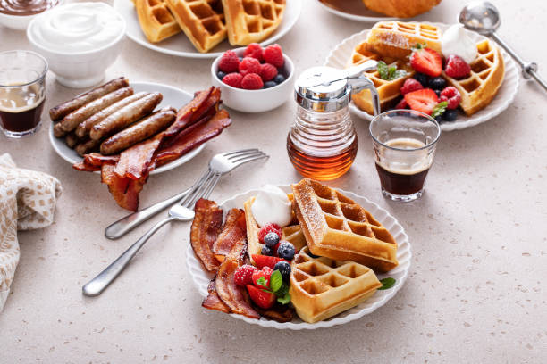 istock Breakfast table with waffles, bacon, breakfast sausage, croissants and berries 1978764044