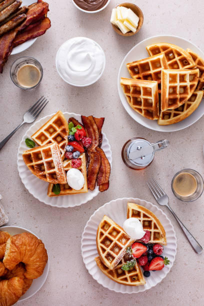 istock Breakfast table with waffles, bacon, breakfast sausage, croissants and berries 1978764046