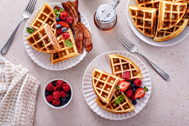 istock Breakfast table with waffles, bacon, breakfast sausage, croissants and berries 1978764050