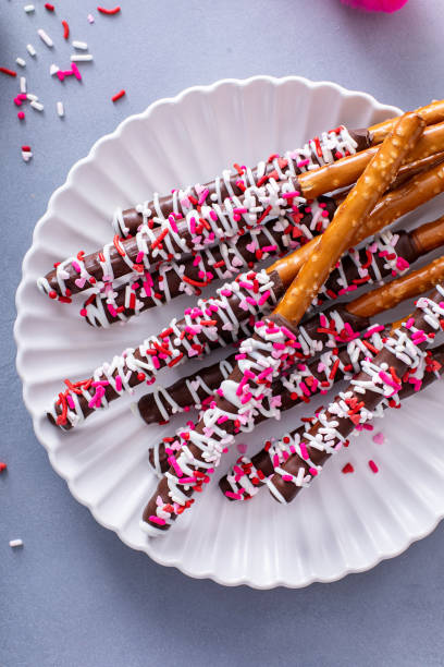 istock Chocolate dipped pretzel rods with pink heart sprinkles on a plate 1978764572