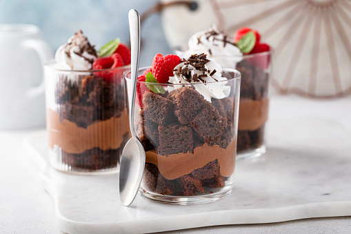 Chocolate mousse and brownie parfait layered in a cup with fresh raspberries