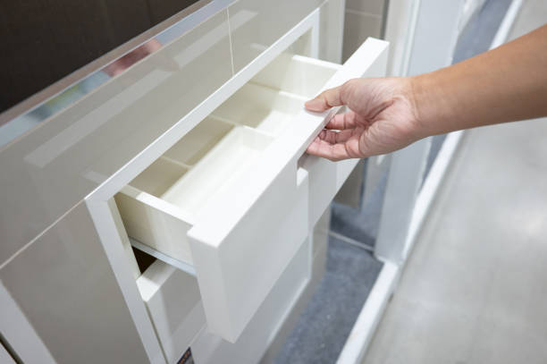 istock Male hand pulling and opening drawer on white wooden cabinet 1978837376