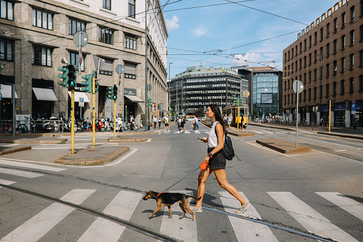 Woman solo traveling through Milan, Italy with her pet dog, enjoying the beautiful streets on a sunny day.